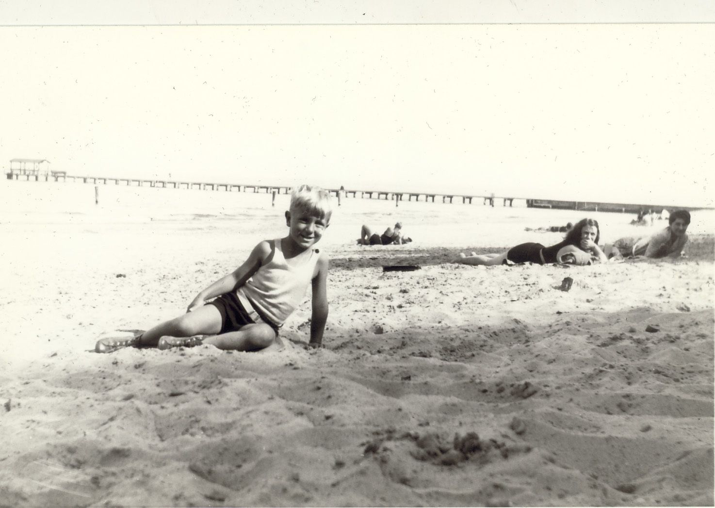 1928. ""Beach with long pier and shelter at lake end.