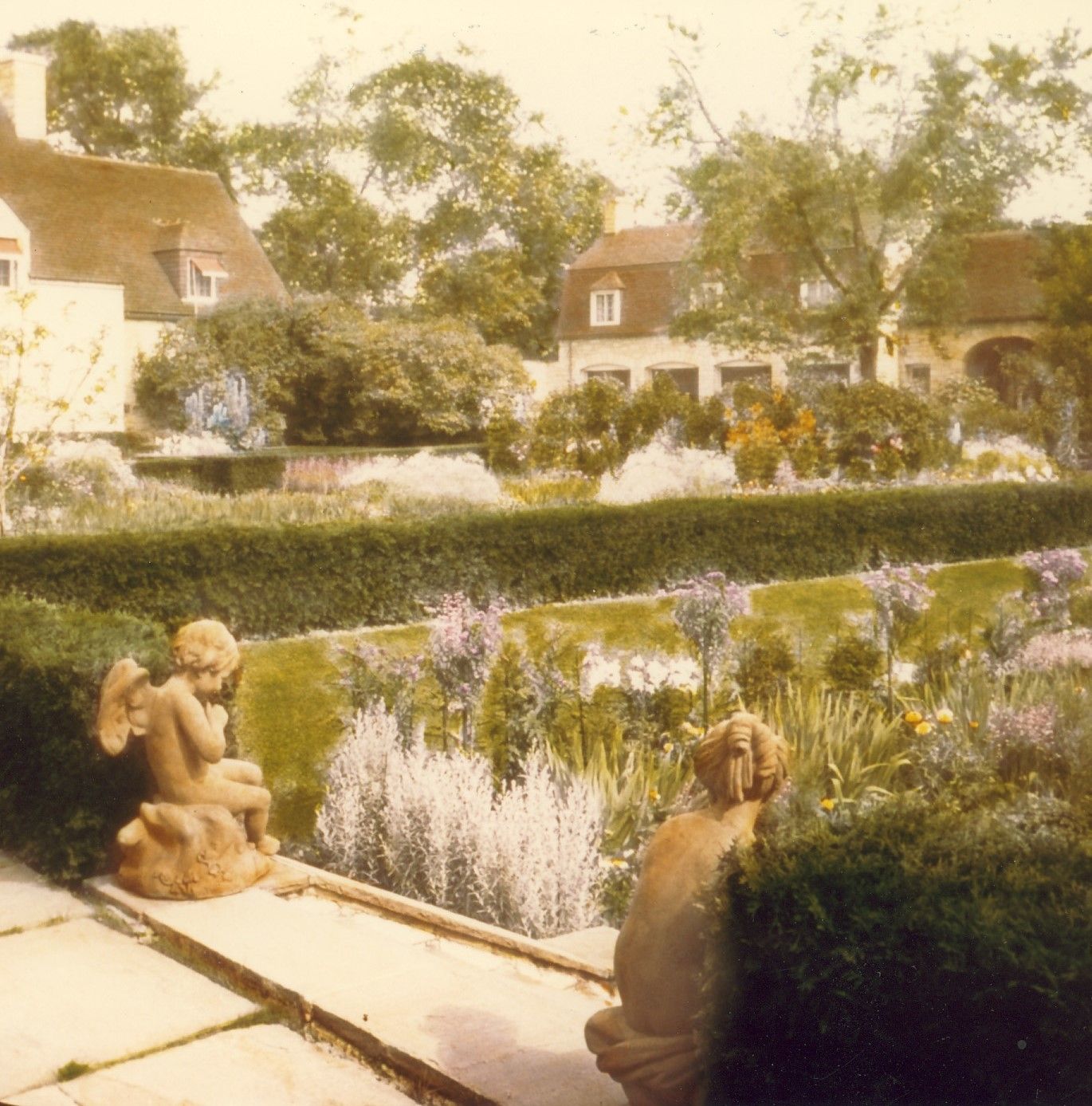 Upper terrace with hedges surrounding lawn statues in foreground.