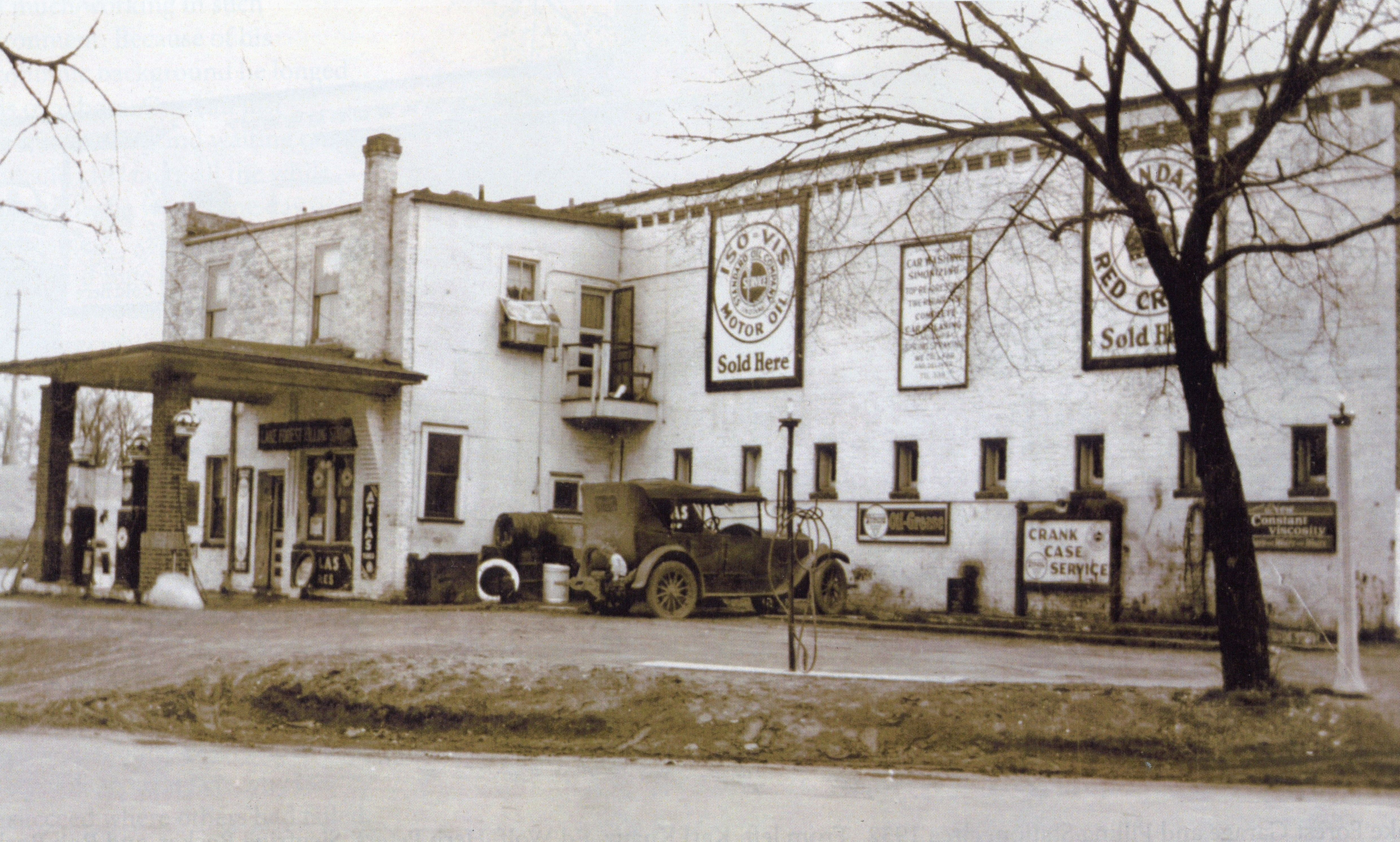 Karl Knauz's son Billy Knauz sitting on the rear bumper of a car at the Lake Forest Filling Station, c. 1932.